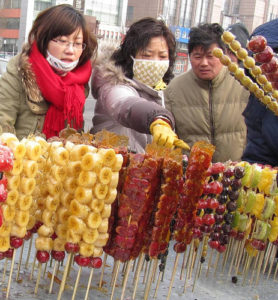 a group of people selling fruit on sticks