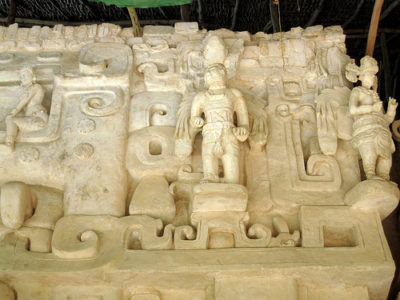 a carved stone wall with a man and people