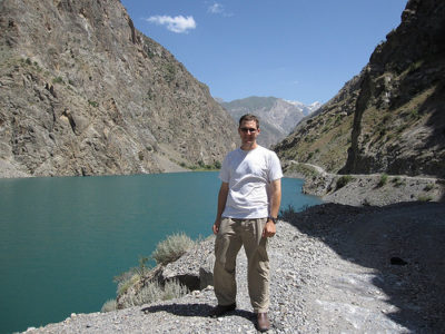 a man standing on a rocky path near a lake