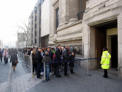 a crowd of people standing in line outside a building