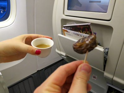 a hand holding a small cup of tea and a small chocolate covered object