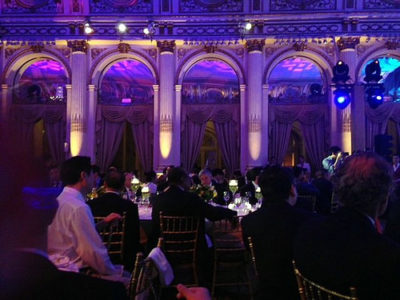 a group of people sitting at tables in a room with purple lights