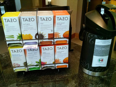 a group of boxes of tea on a rack next to a trash can