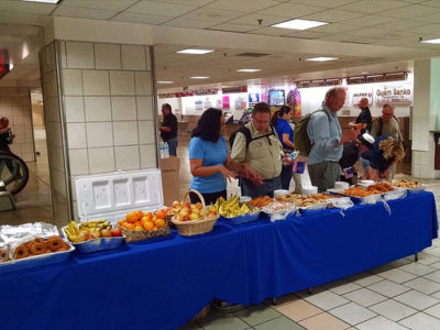 a group of people standing around a table with food