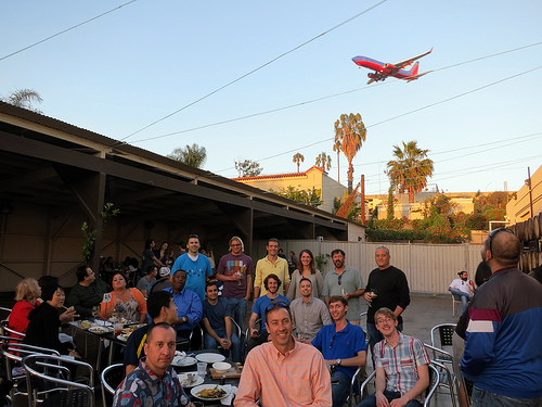 a group of people sitting at tables and a plane flying in the sky