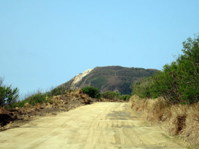 a dirt road with a hill in the background