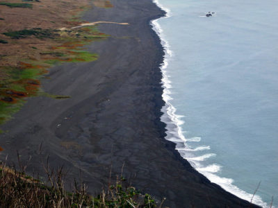 a black sand beach with waves crashing on the shore