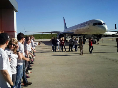 a group of people standing in a line next to an airplane