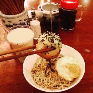 a bowl of noodles with a bun and an egg