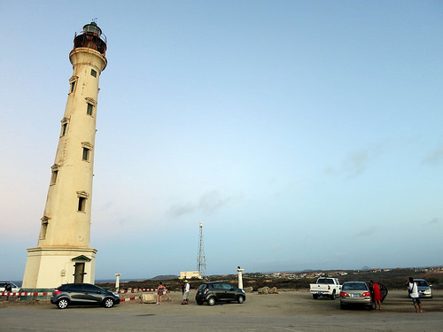a lighthouse with cars parked on the beach