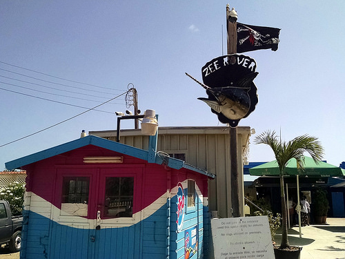 a sign on a pole with a swordfish and a flag on it