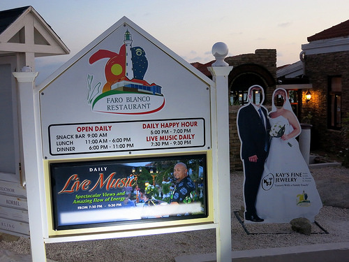 a sign with cut out images of a couple of people and a man standing in front of a building