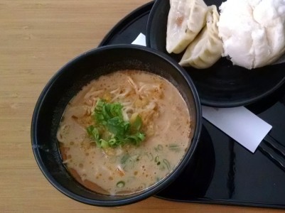 a bowl of soup next to dumplings