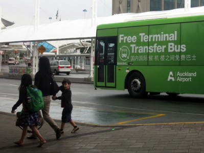a group of people walking by a green bus