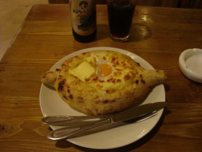 a bread with a egg on it on a plate with a bottle of beer and a glass of liquid